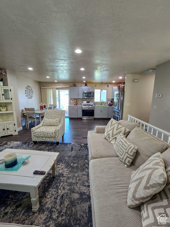 Living area featuring recessed lighting, dark wood-style flooring, and a textured ceiling