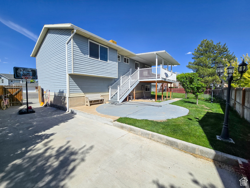 Back of property featuring stairs, a patio area, a lawn, and fence