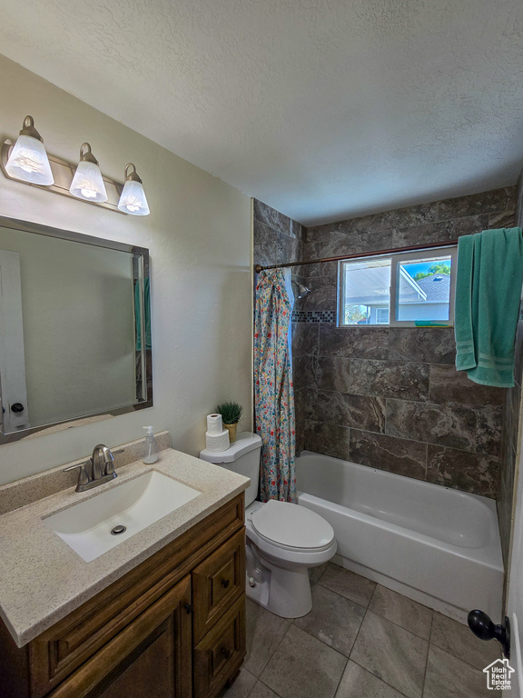 Full bathroom featuring vanity, toilet, a textured ceiling, tile patterned floors, and shower / tub combo