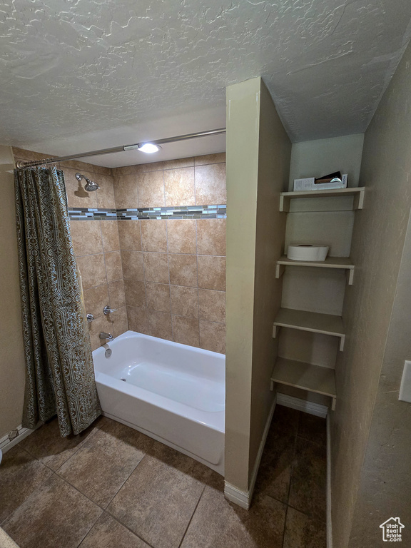 Bathroom featuring baseboards, tile patterned flooring, a textured ceiling, and shower / tub combo with curtain