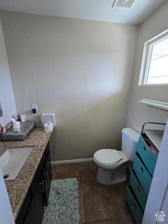 Bathroom featuring tile patterned flooring, vanity, toilet, baseboards, and visible vents