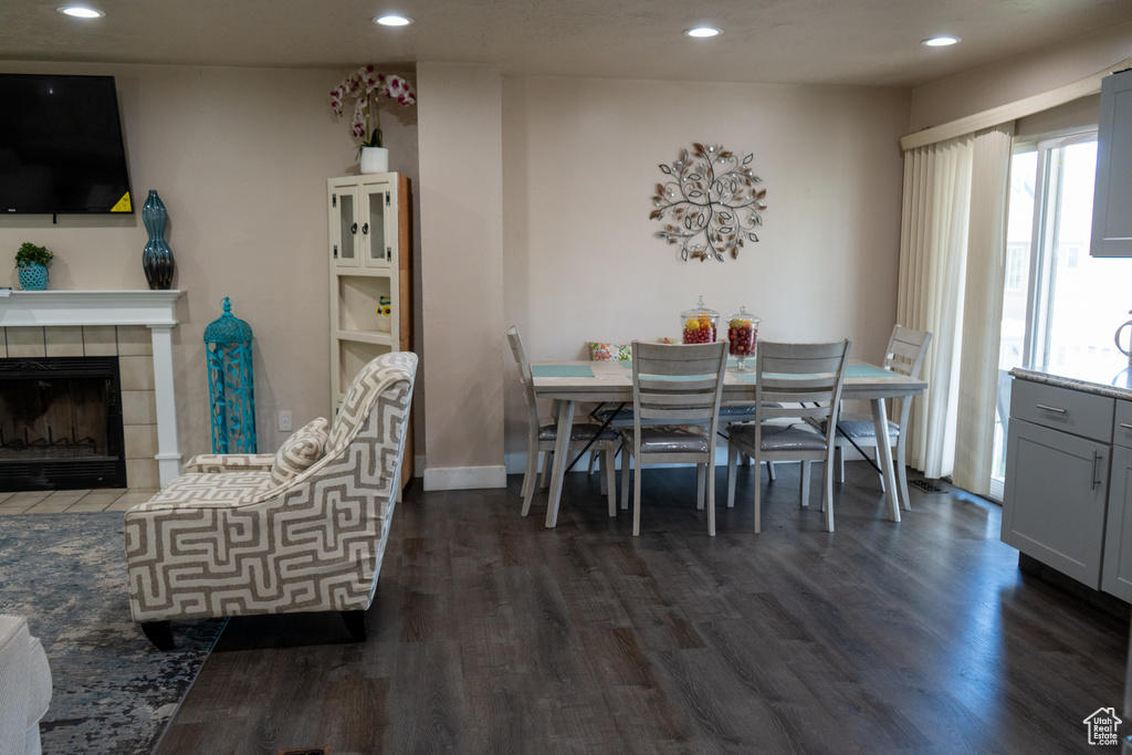 Dining space featuring dark wood-style flooring, recessed lighting, and a fireplace
