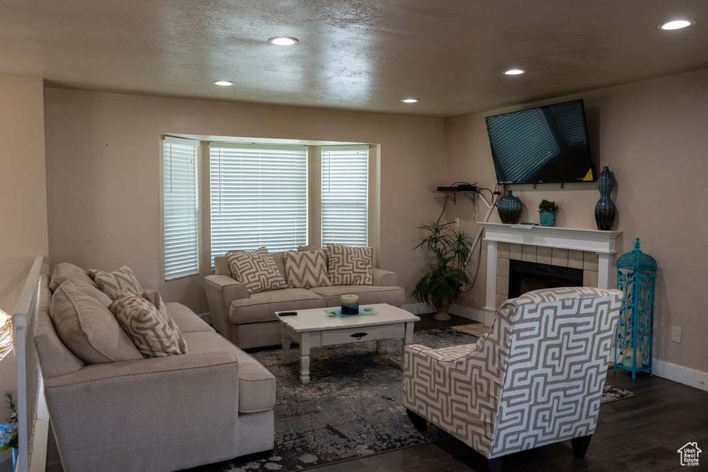 Living room featuring baseboards, recessed lighting, dark wood-style flooring, and a tile fireplace