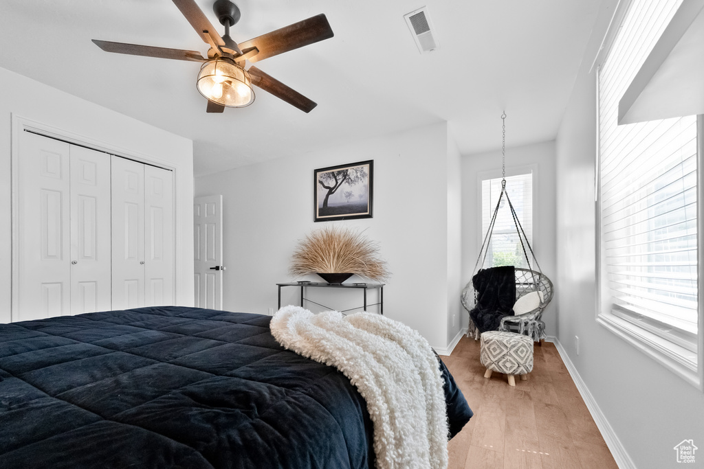 Bedroom featuring visible vents, a closet, baseboards, a ceiling fan, and light wood finished floors