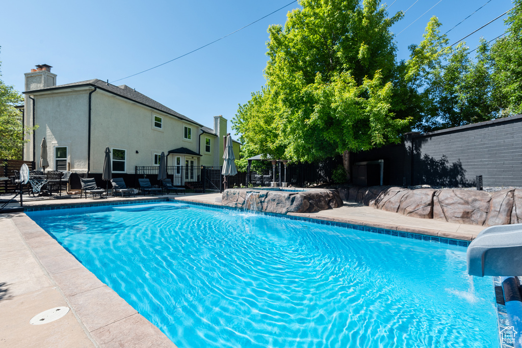 View of swimming pool with a water slide and a patio area