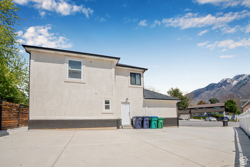 Rear view of property featuring stucco siding, a mountain view, fence, and a patio
