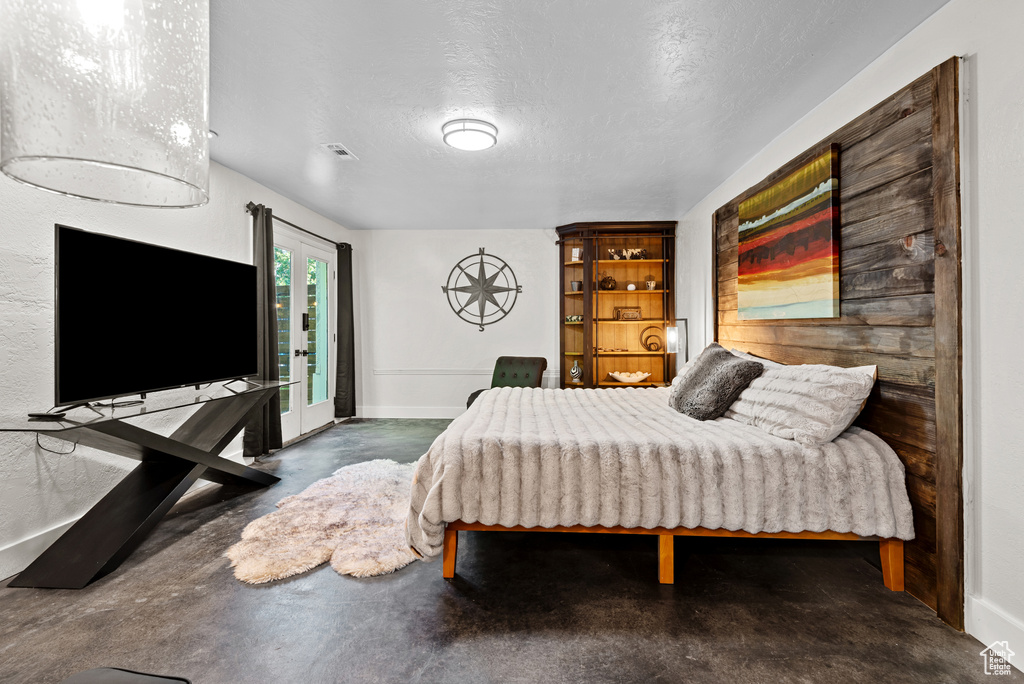 Bedroom with finished concrete floors, baseboards, and a textured ceiling