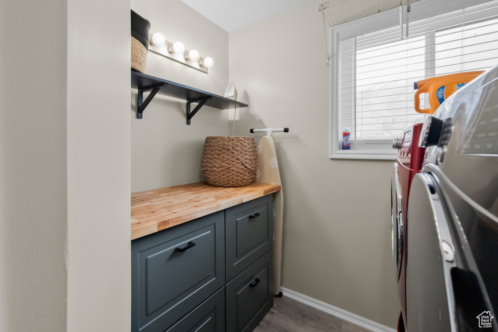 Laundry room with baseboards, wood finished floors, cabinet space, and washing machine and clothes dryer