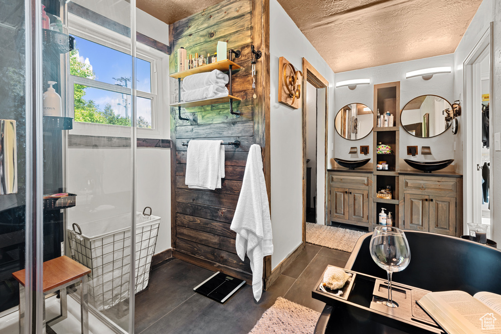 Bathroom with a textured ceiling, wood finished floors, double vanity, and baseboards