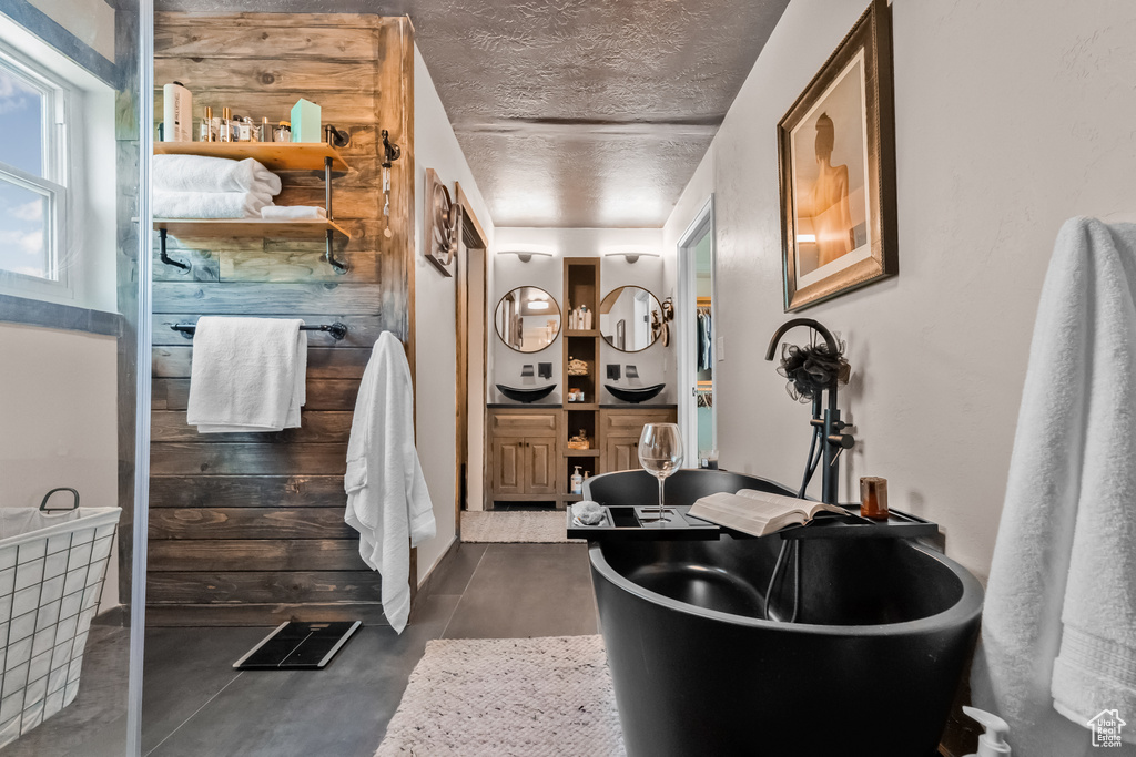 Full bath featuring finished concrete floors, a textured ceiling, and a freestanding tub