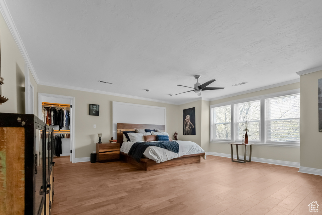 Bedroom with baseboards, visible vents, ornamental molding, and light wood finished floors