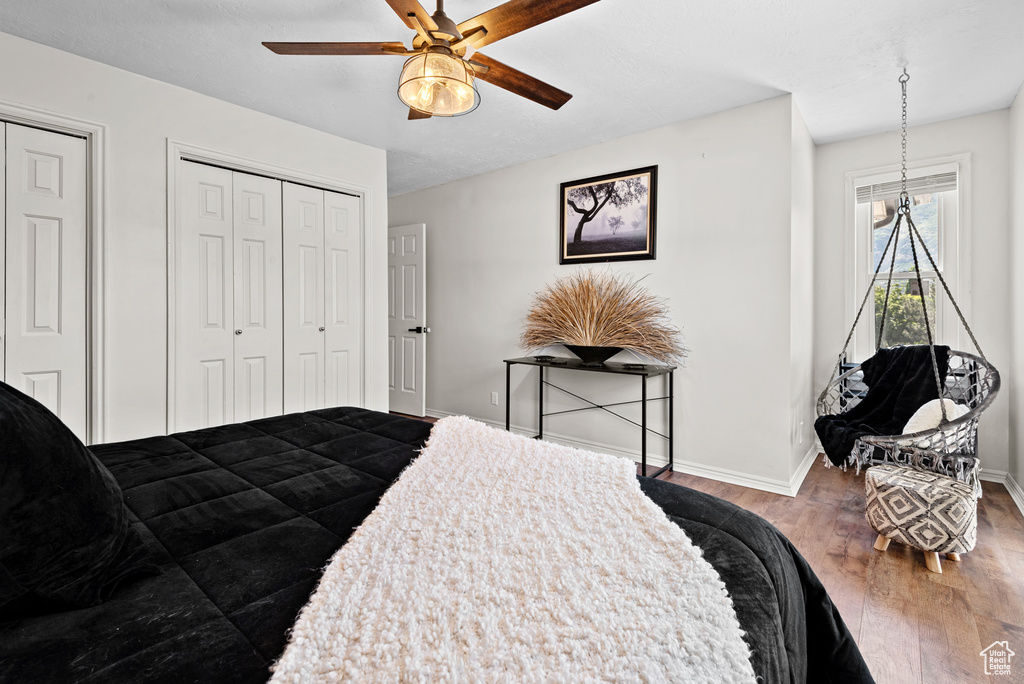 Bedroom with wood finished floors, baseboards, two closets, and a ceiling fan