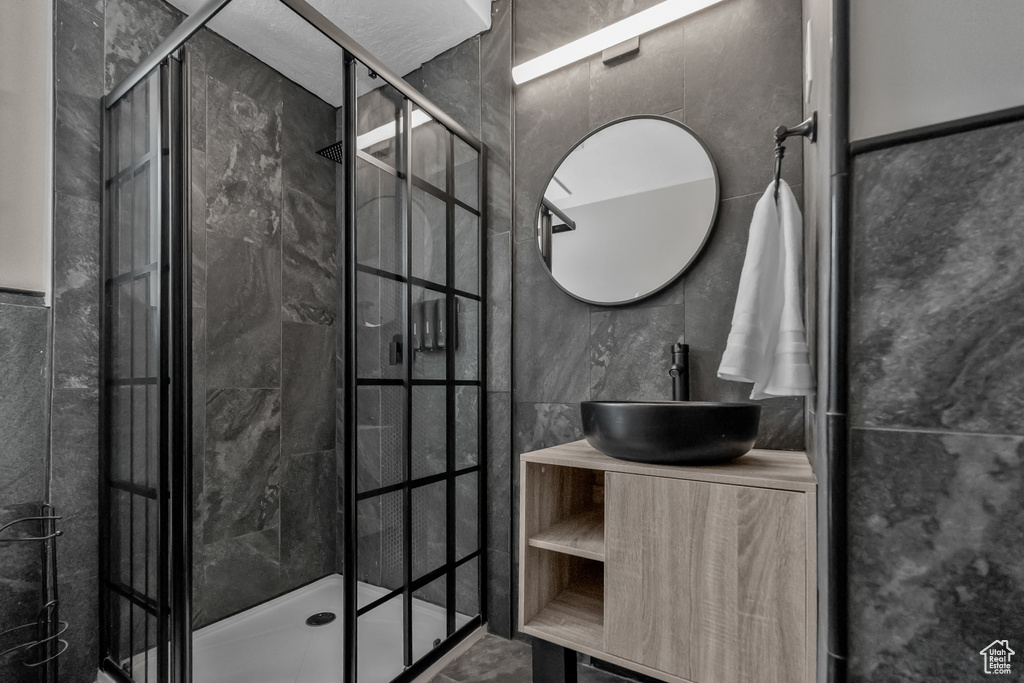 Full bath featuring vanity, a shower stall, and tile walls