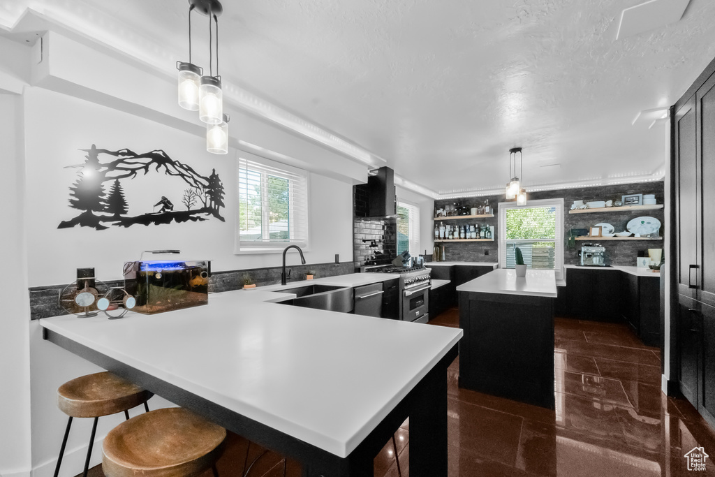 Kitchen featuring a kitchen island, open shelves, light countertops, a sink, and stainless steel appliances