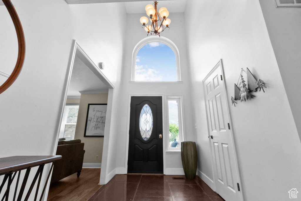 Foyer with baseboards, a notable chandelier, and a towering ceiling