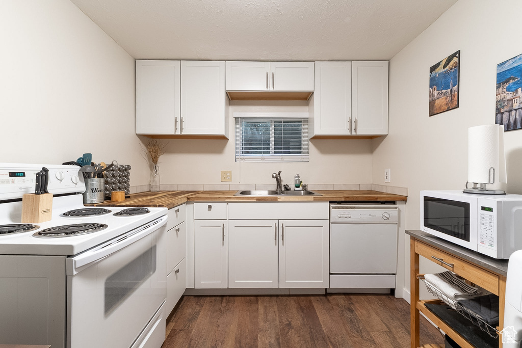 Kitchen with dark wood-style flooring, white appliances, butcher block countertops, white cabinets, and a sink