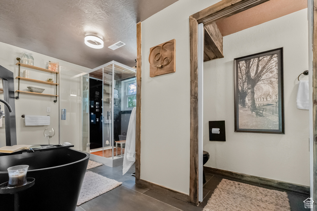 Bathroom featuring baseboards, a stall shower, a textured ceiling, and visible vents