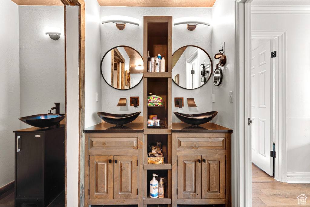 Bathroom with double vanity, wood finished floors, and baseboards