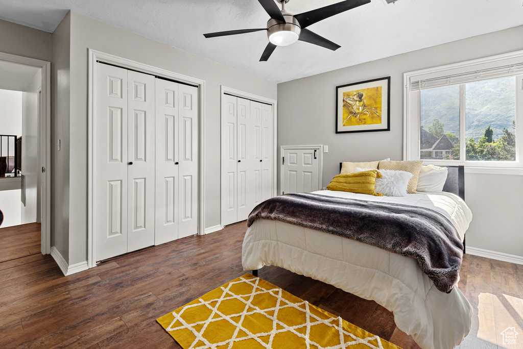Bedroom with multiple closets, baseboards, wood finished floors, and ceiling fan