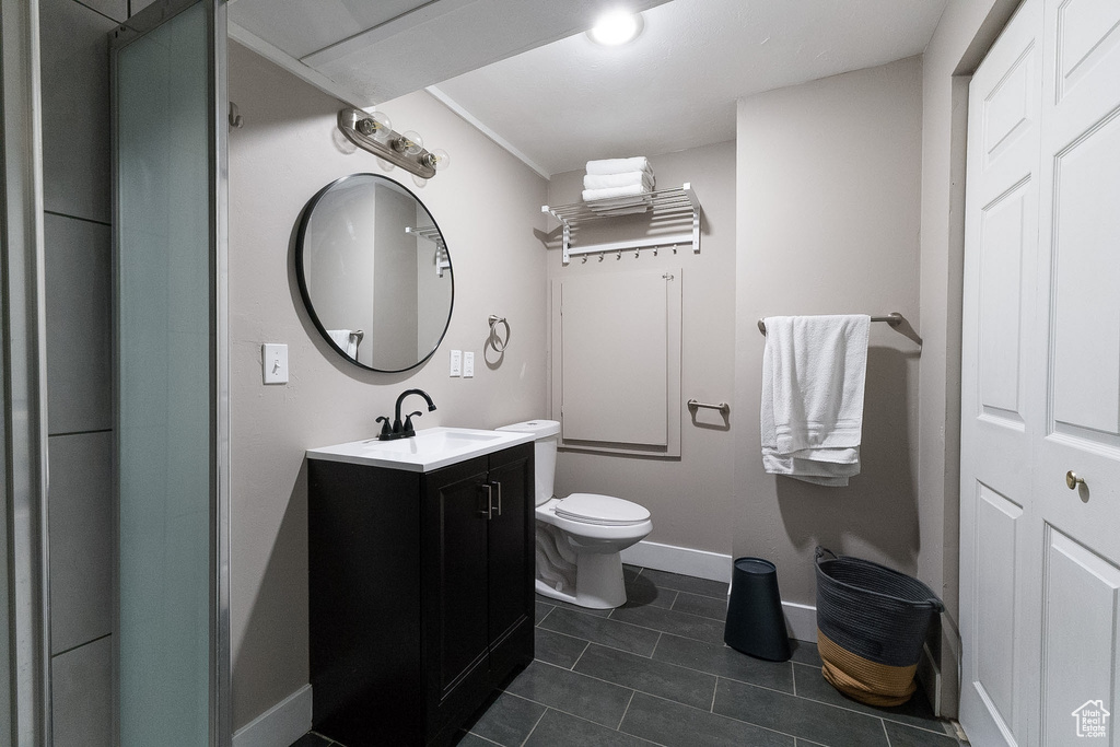 Bathroom with toilet, baseboards, tile patterned flooring, and vanity