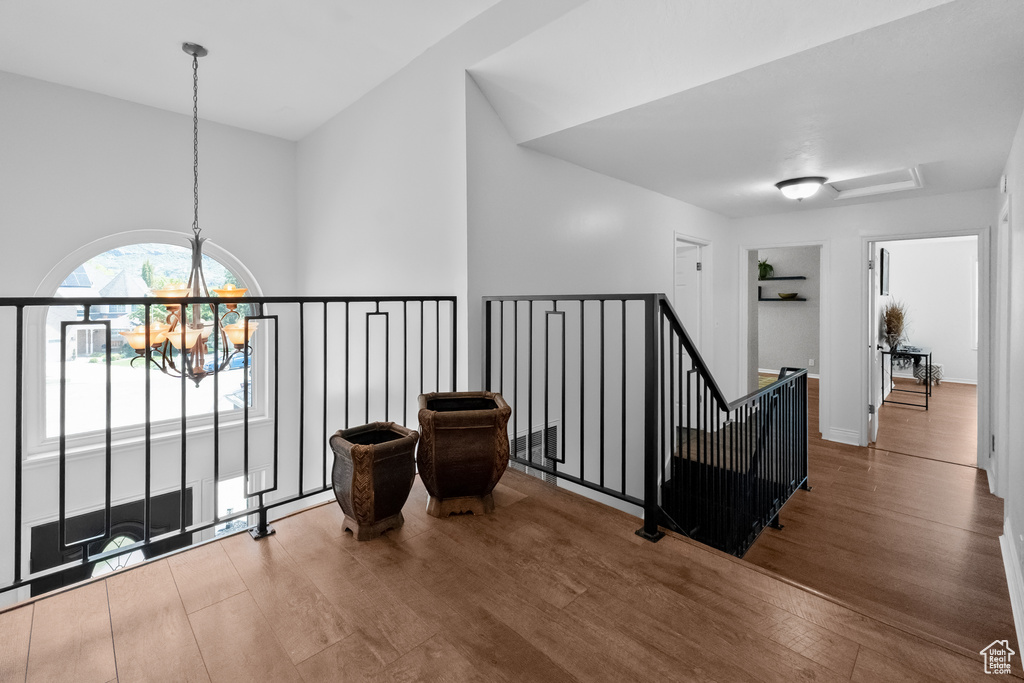 Hallway featuring a chandelier, wood finished floors, and an upstairs landing