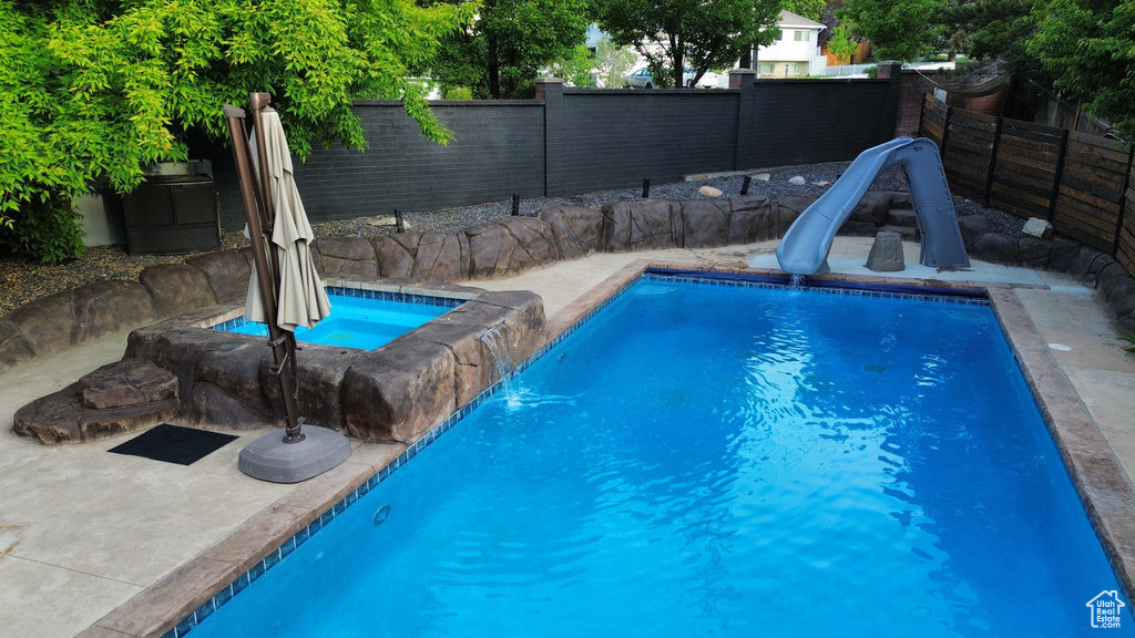 View of swimming pool featuring a water slide and a fenced backyard