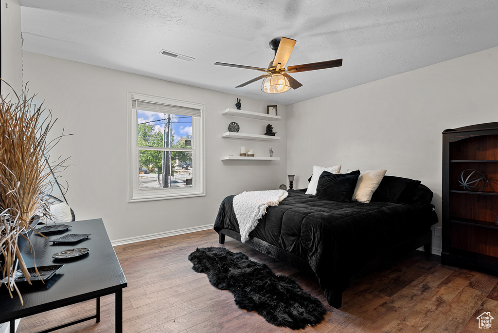 Bedroom with hardwood / wood-style floors, baseboards, and a ceiling fan