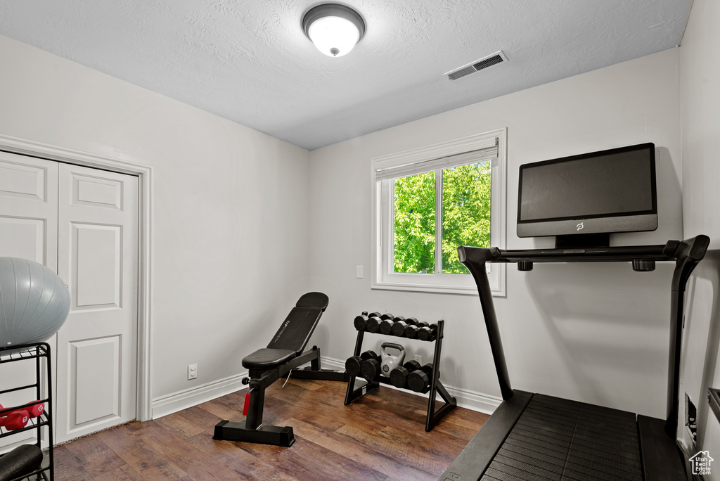 Workout area with wood finished floors, baseboards, and a textured ceiling