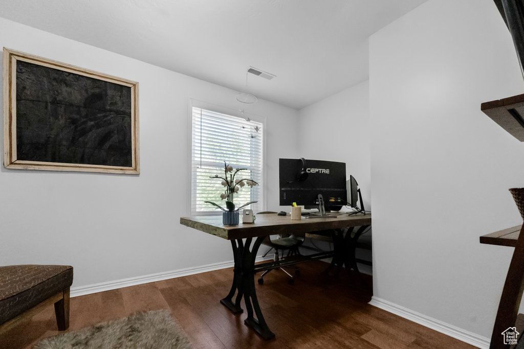 Office area featuring baseboards, visible vents, and wood finished floors