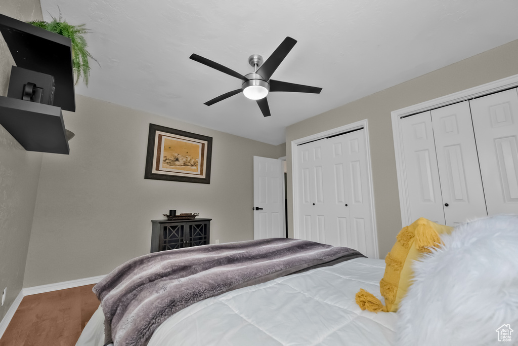 Bedroom with baseboards, ceiling fan, two closets, and wood finished floors