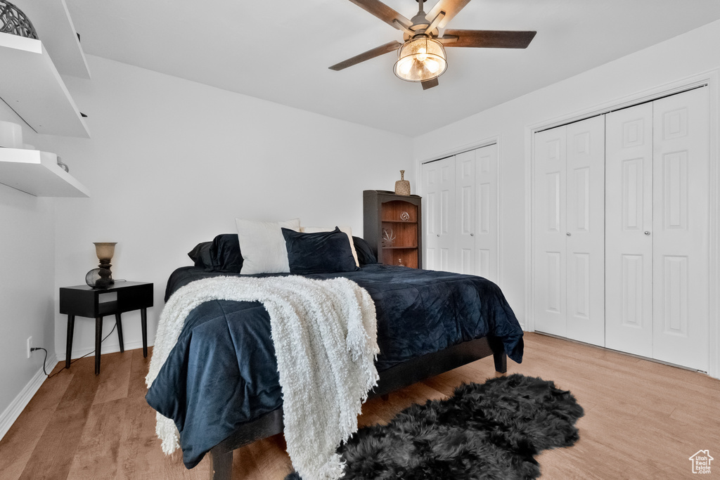Bedroom with two closets, a ceiling fan, baseboards, and wood finished floors