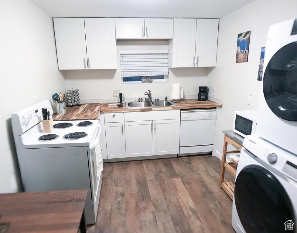 Kitchen featuring a sink, stacked washer and clothes dryer, white appliances, and butcher block counters