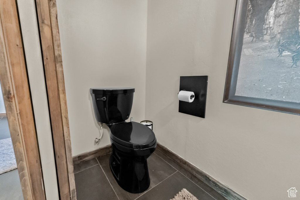 Bathroom featuring baseboards, tile patterned floors, and toilet