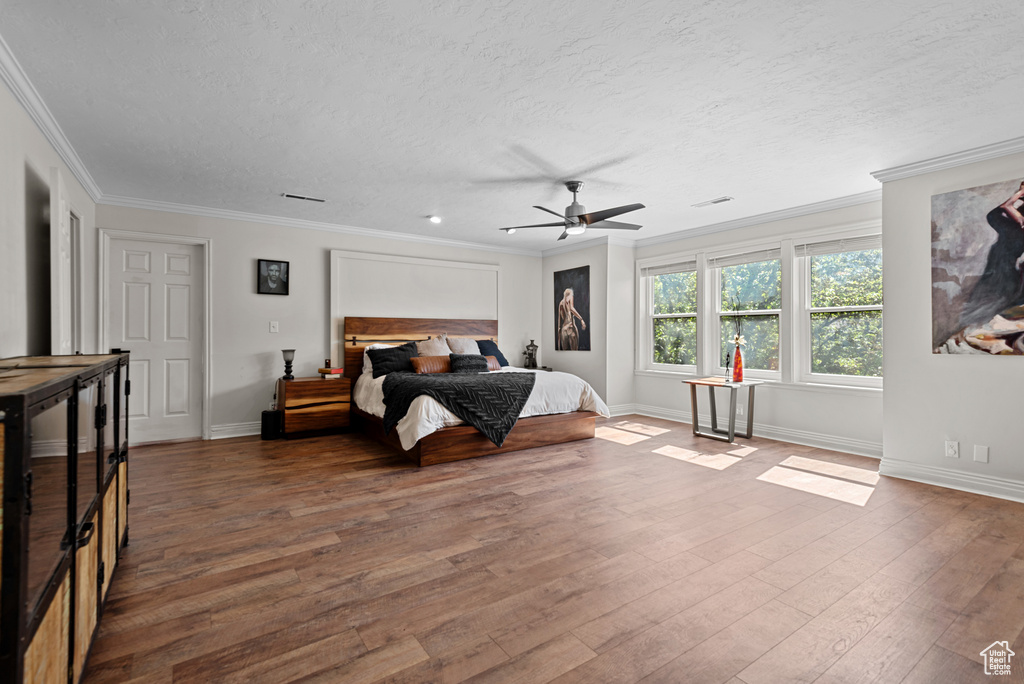 Bedroom featuring ornamental molding, wood finished floors, a textured ceiling, baseboards, and ceiling fan