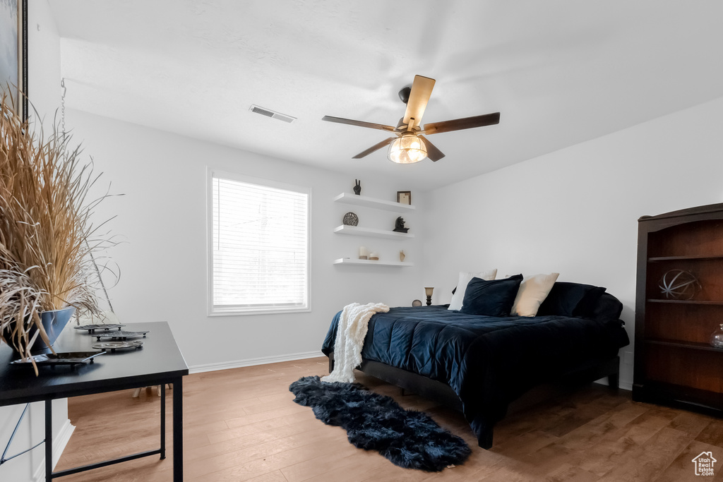 Bedroom with baseboards, a ceiling fan, wood finished floors, and visible vents