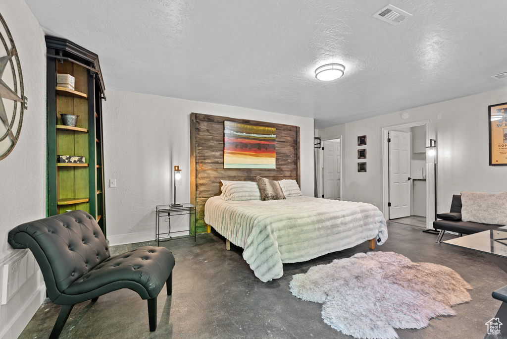 Bedroom with a textured ceiling and concrete flooring