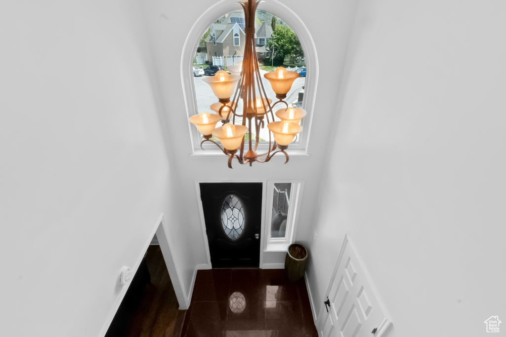 Foyer featuring baseboards, granite finish floor, a towering ceiling, and a chandelier