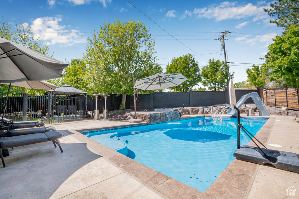 View of pool featuring a patio, a water slide, a fenced backyard, and a fenced in pool