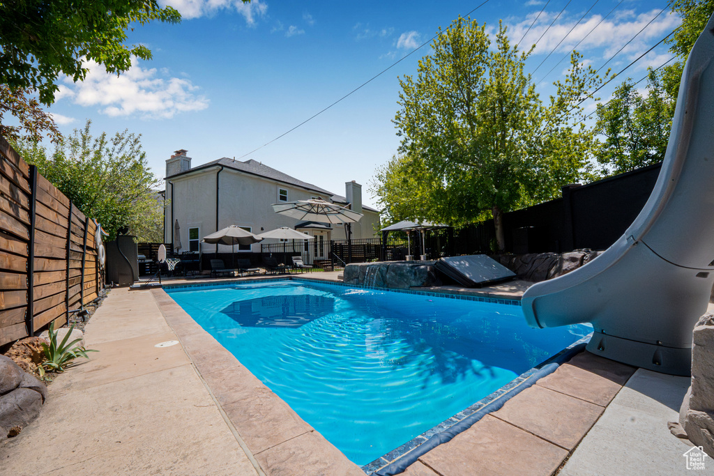 View of pool featuring a patio, a water slide, a fenced backyard, and a fenced in pool