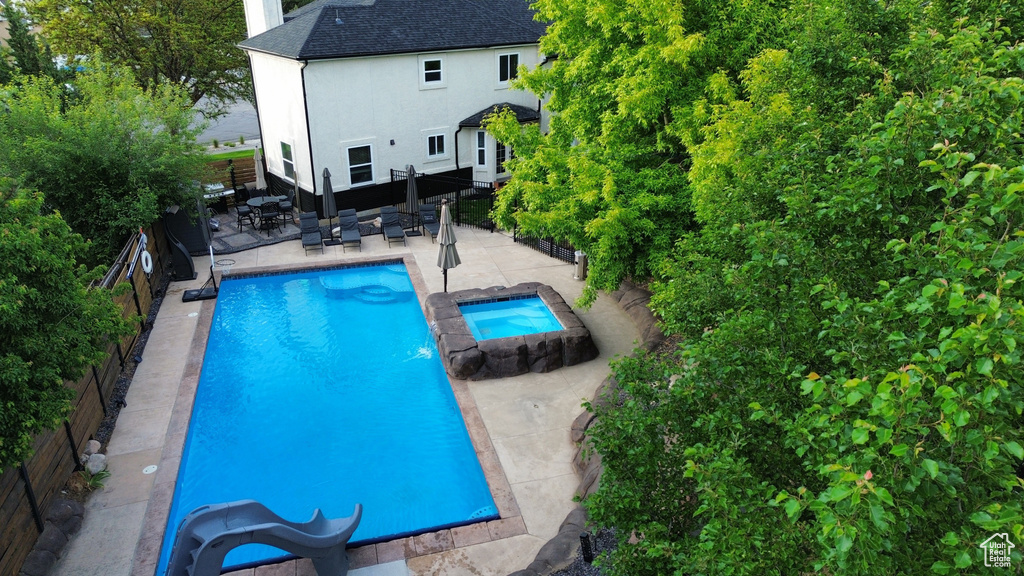 View of swimming pool with a fenced backyard, a patio area, and a pool with connected hot tub