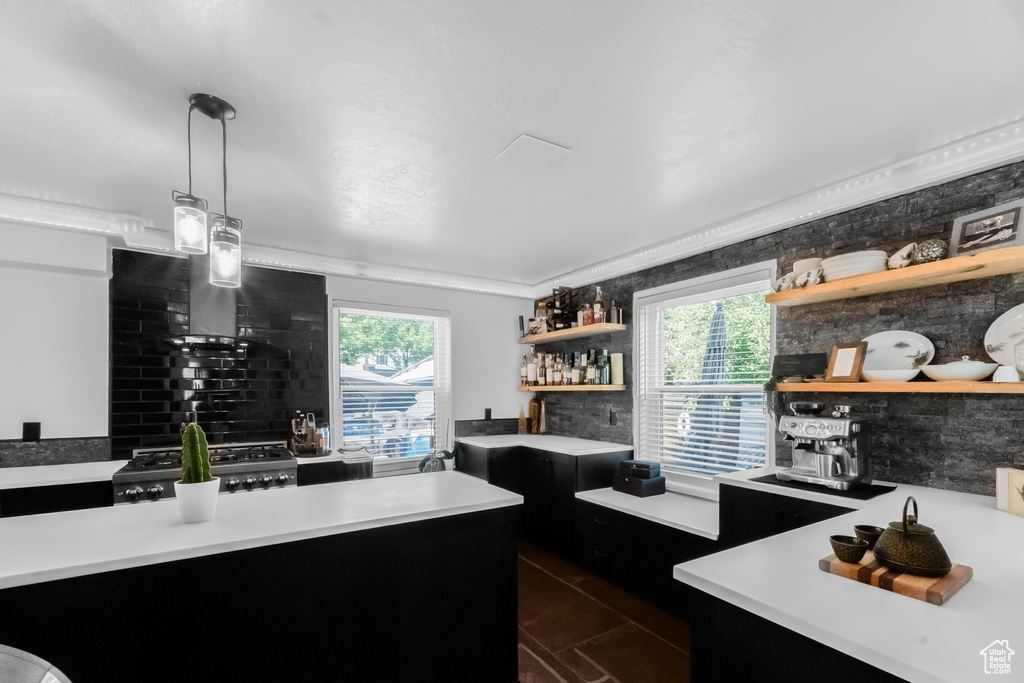 Kitchen with open shelves, light countertops, dark cabinetry, range, and decorative light fixtures