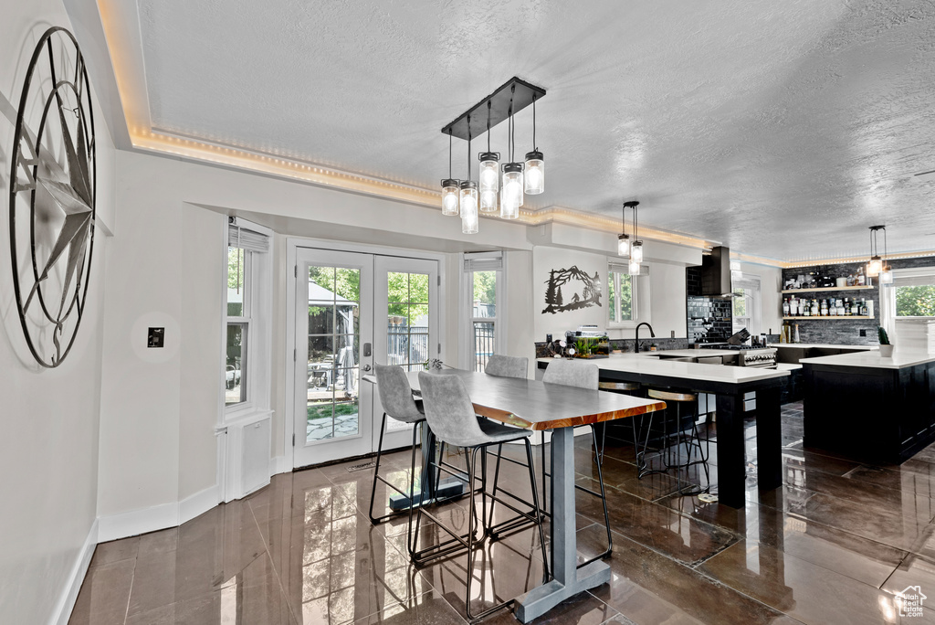 Dining room featuring plenty of natural light, a textured ceiling, baseboards, and french doors