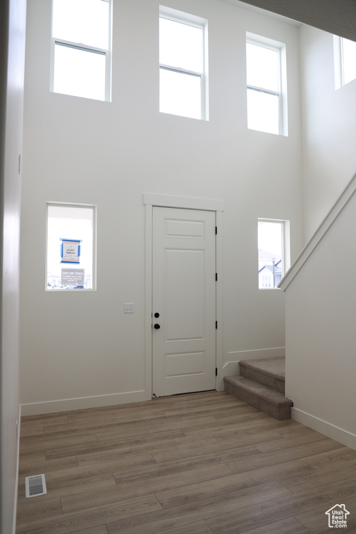 Entrance foyer with a high ceiling, visible vents, wood finished floors, and stairway