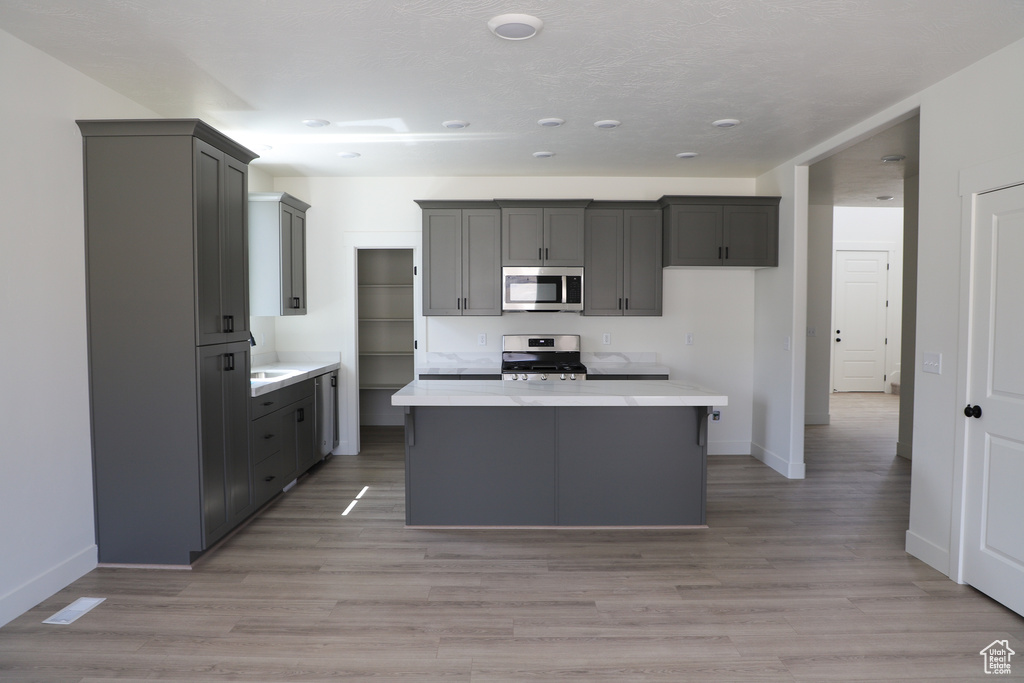 Kitchen featuring light countertops, baseboards, a kitchen island, and stainless steel appliances