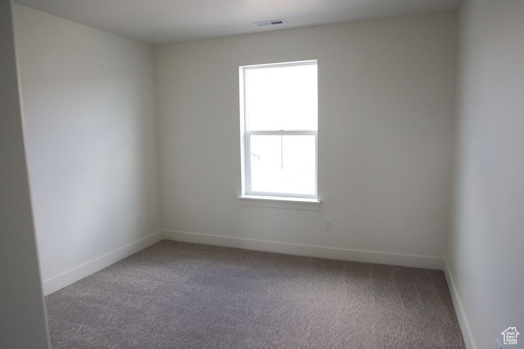 Empty room with baseboards, visible vents, and carpet