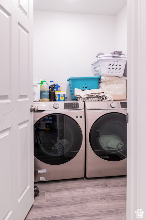 Laundry area with separate washer and dryer, laundry area, and wood finished floors