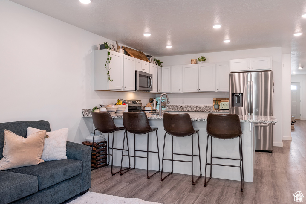 Kitchen with a peninsula, white cabinetry, appliances with stainless steel finishes, and open floor plan