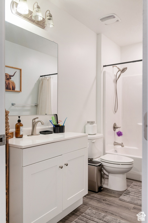 Full bath with visible vents, vanity, wood finished floors, shower / bath combination with curtain, and toilet