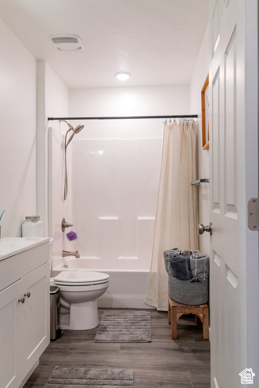 Full bath featuring shower / bath combo with shower curtain, visible vents, vanity, wood finished floors, and toilet