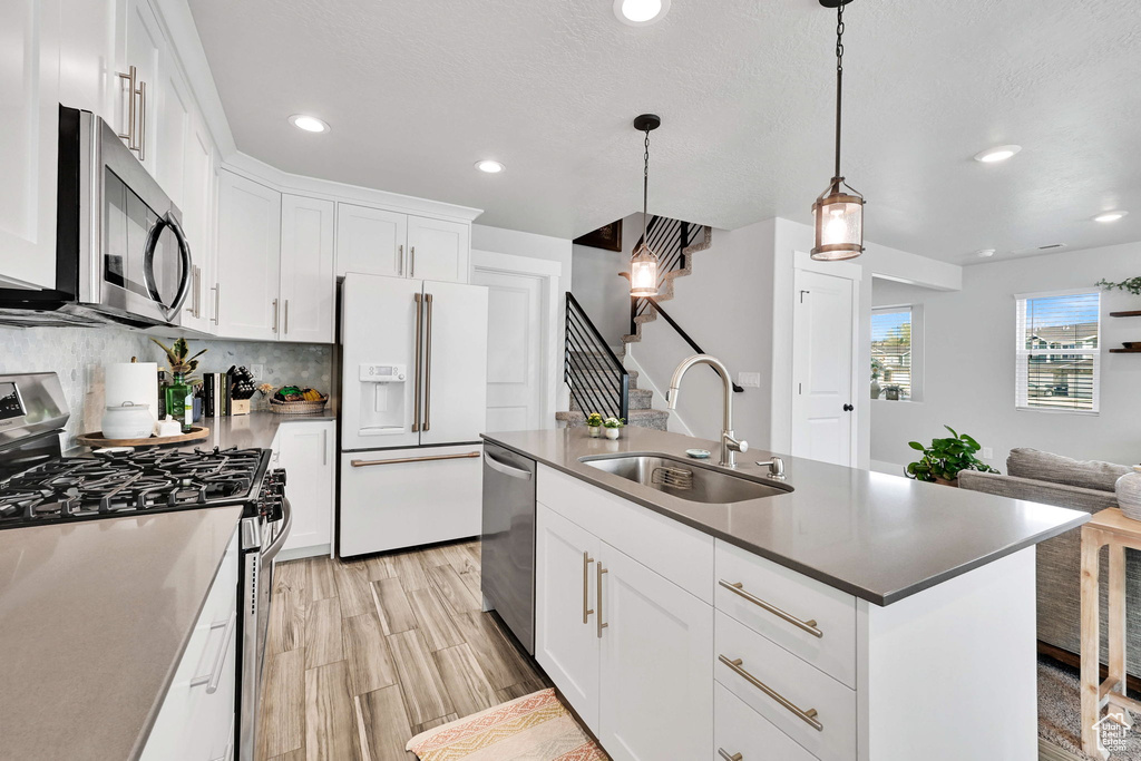 Kitchen with a sink, stainless steel appliances, open floor plan, recessed lighting, and white cabinetry